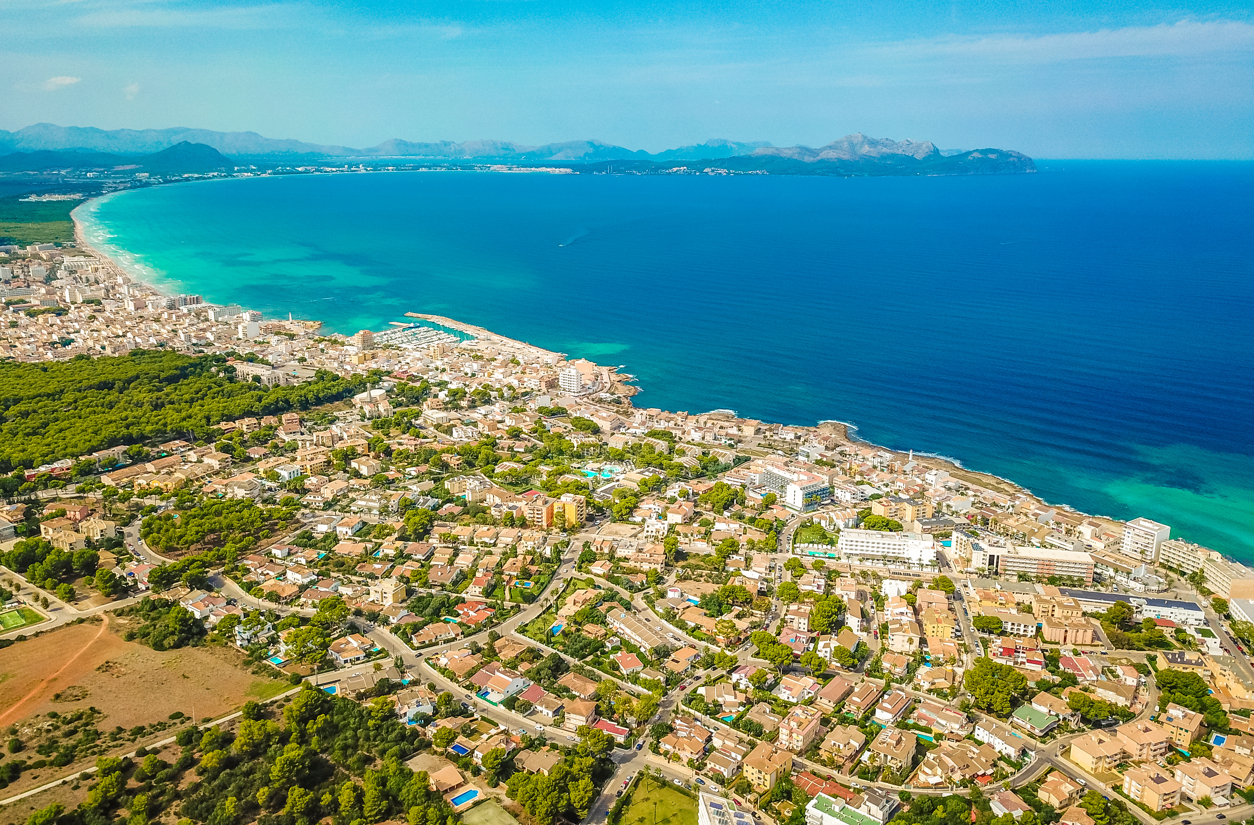 Vista de pájaro sobre el pueblo de Can Picafort con Alcudia en el horizonte