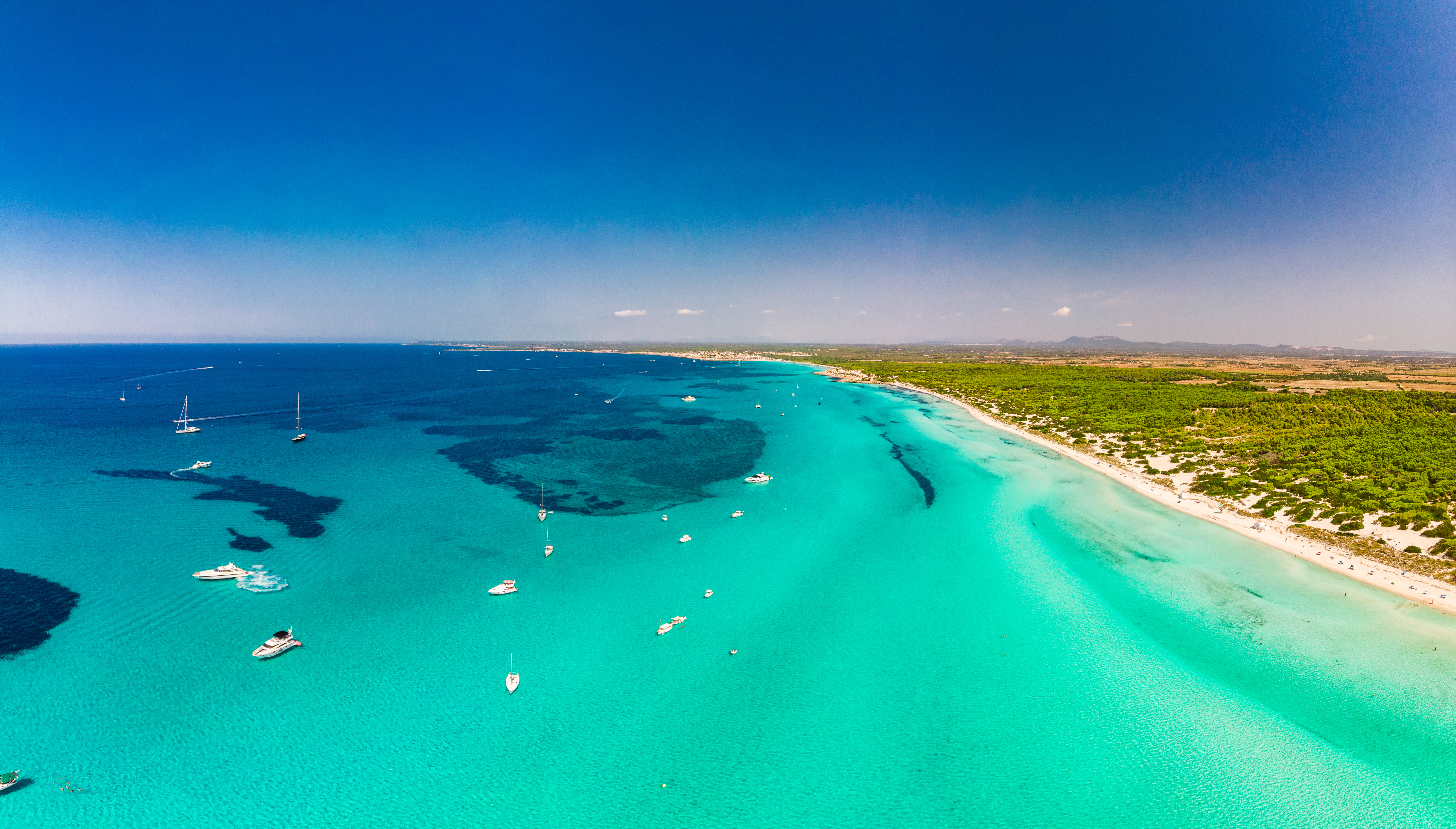 From a bird's eye view - Some boats in the beautiful turquoise Mediterranean on the bright white sandy beach of Es Trenc