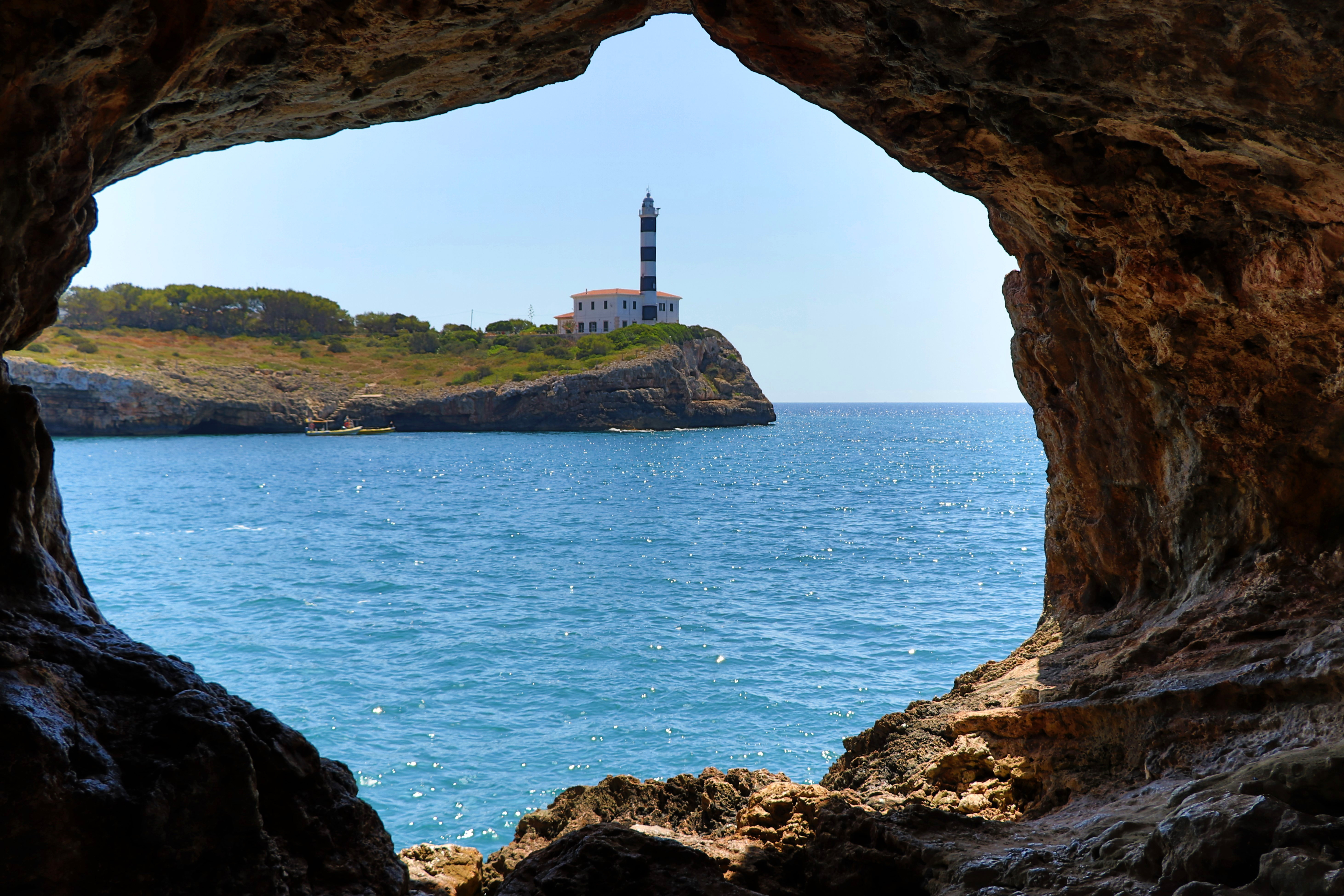 Kilátás egy sziklában lévő ablakon keresztül a Porto Colom világítótoronyra