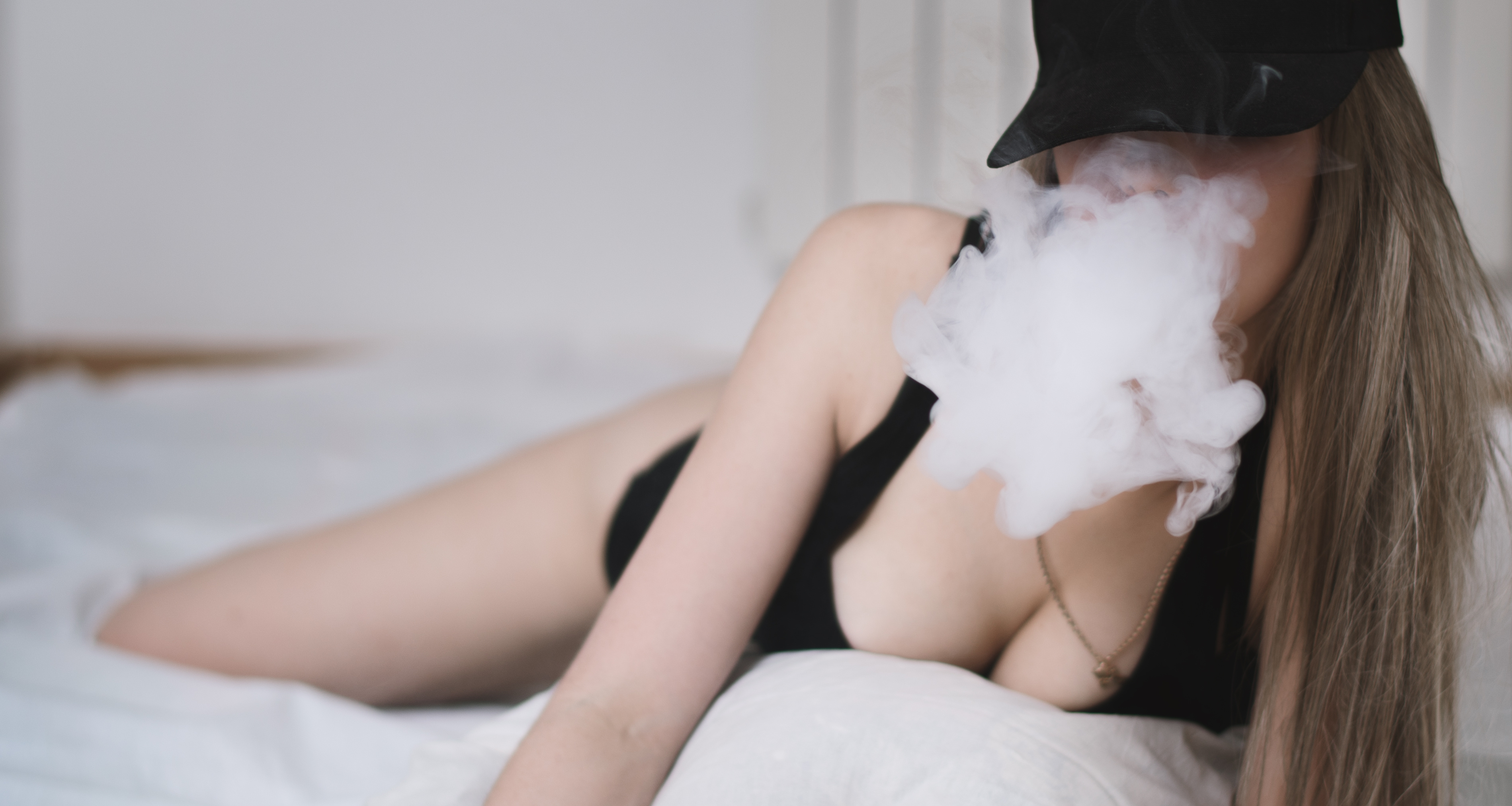 Femme fumant du cannabis sexy sur le lit, acheté dans un club social de cannabis (CSC) à Majorque