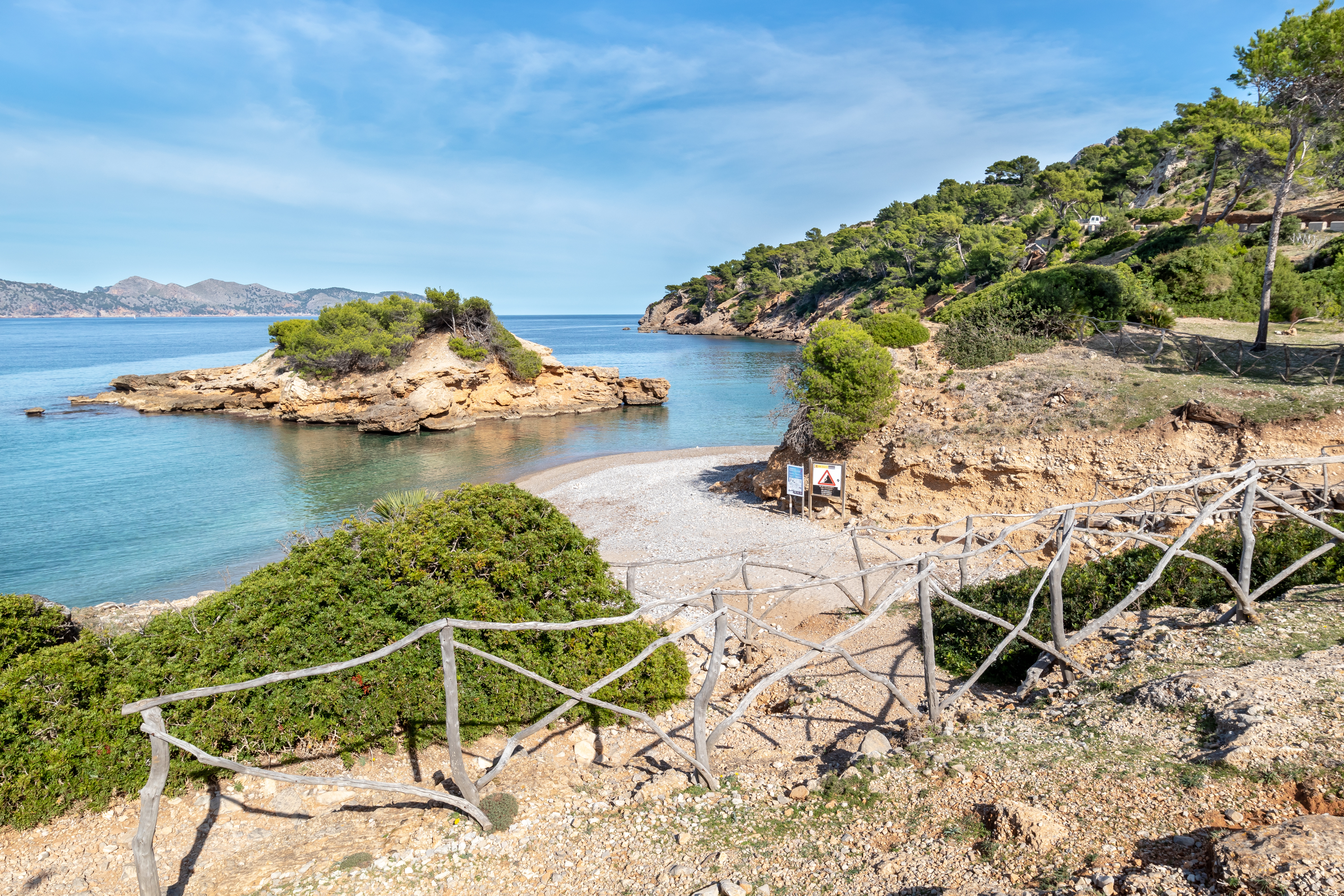 Sentiero escursionistico a S'Illot che porta a una piccola baia balneare con un'isola di fronte