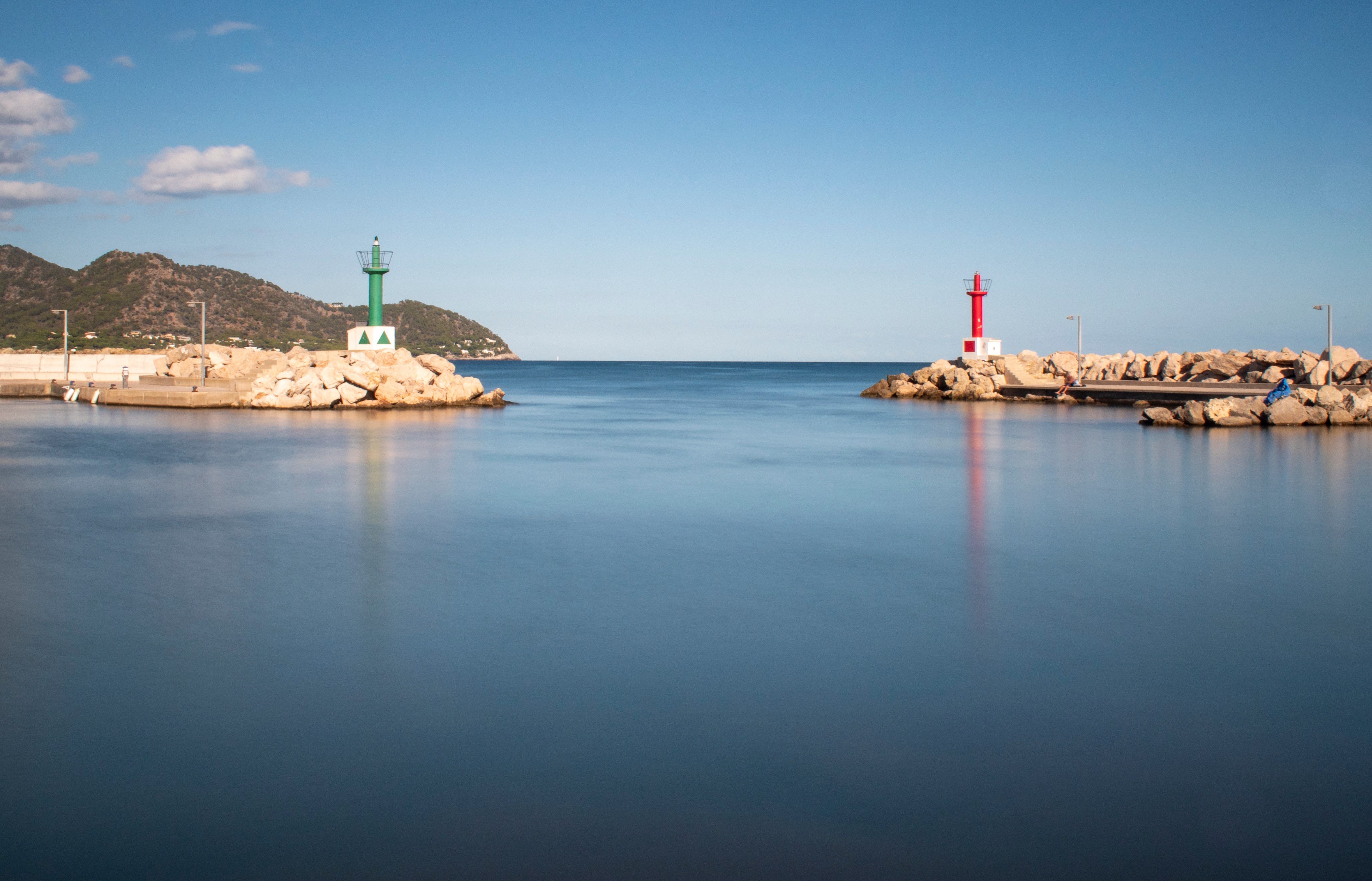 Vjezd do přístavu v Cala Bona. Hladká tmavě modrá voda obklopená skalami