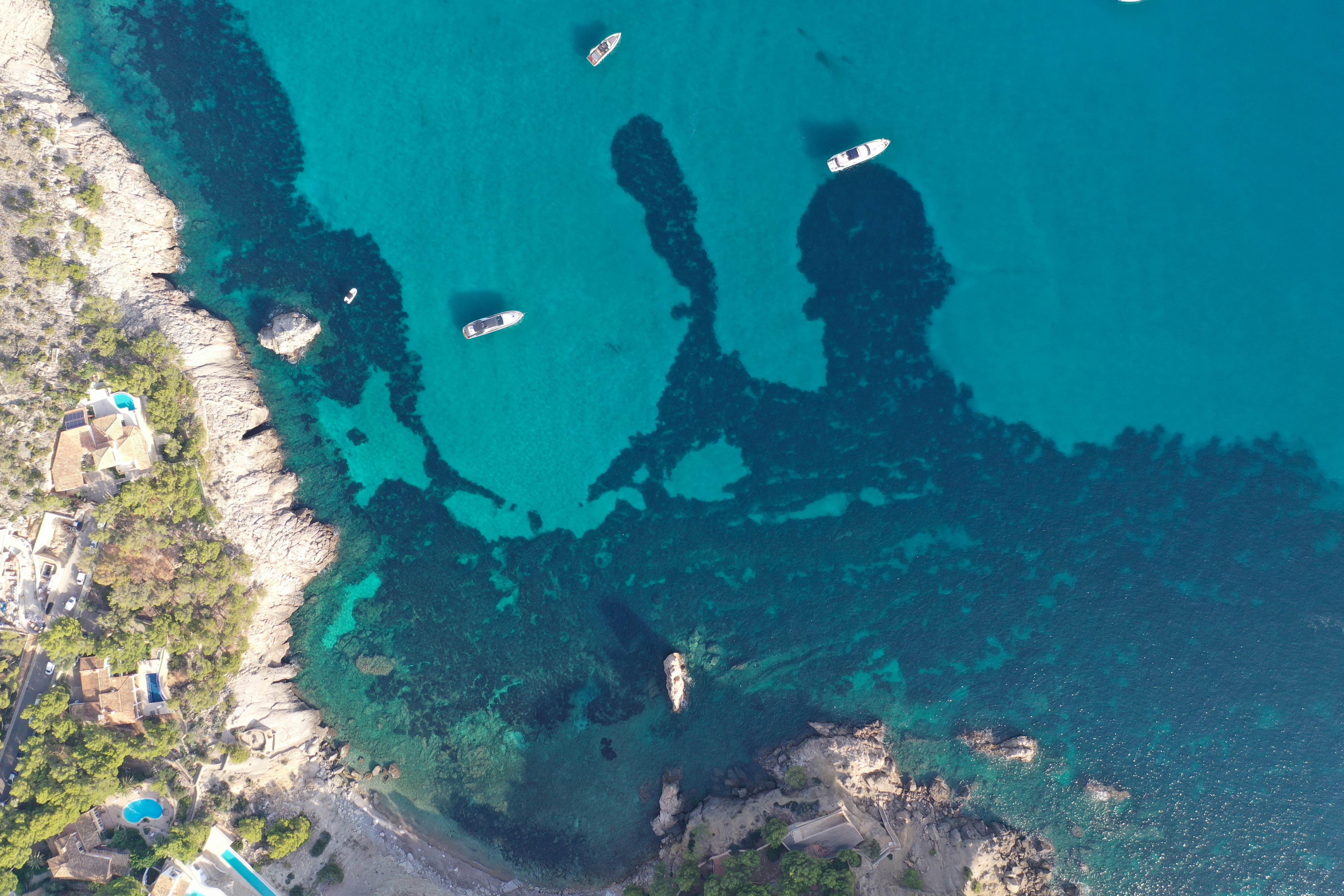 Vista aerea della fantastica baia di Camp de Mar. Nelle acque blu scuro ci sono piccole barche bianche