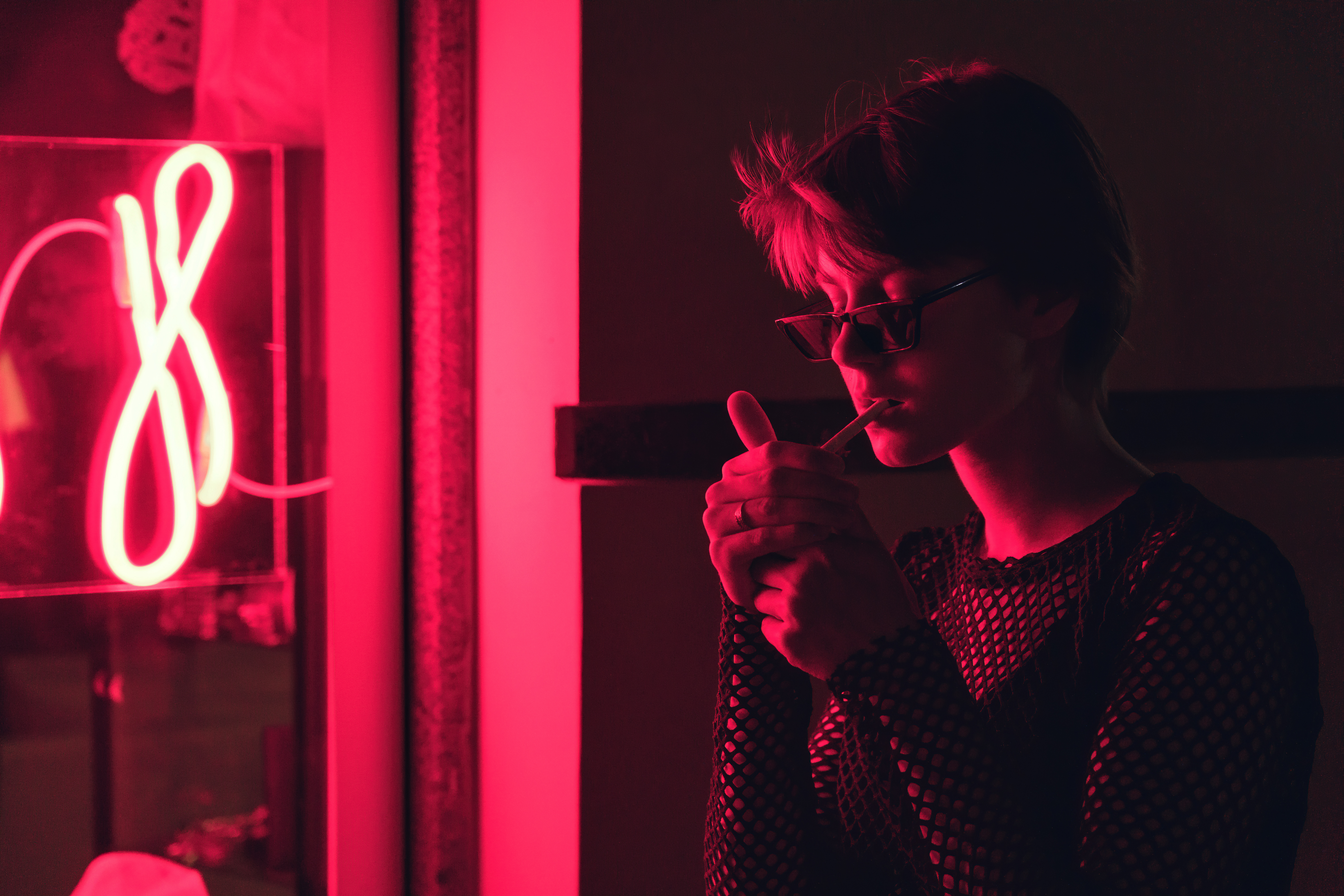 Woman lighting joint under red light in a Cannabis Social Club (CSC) in Artà