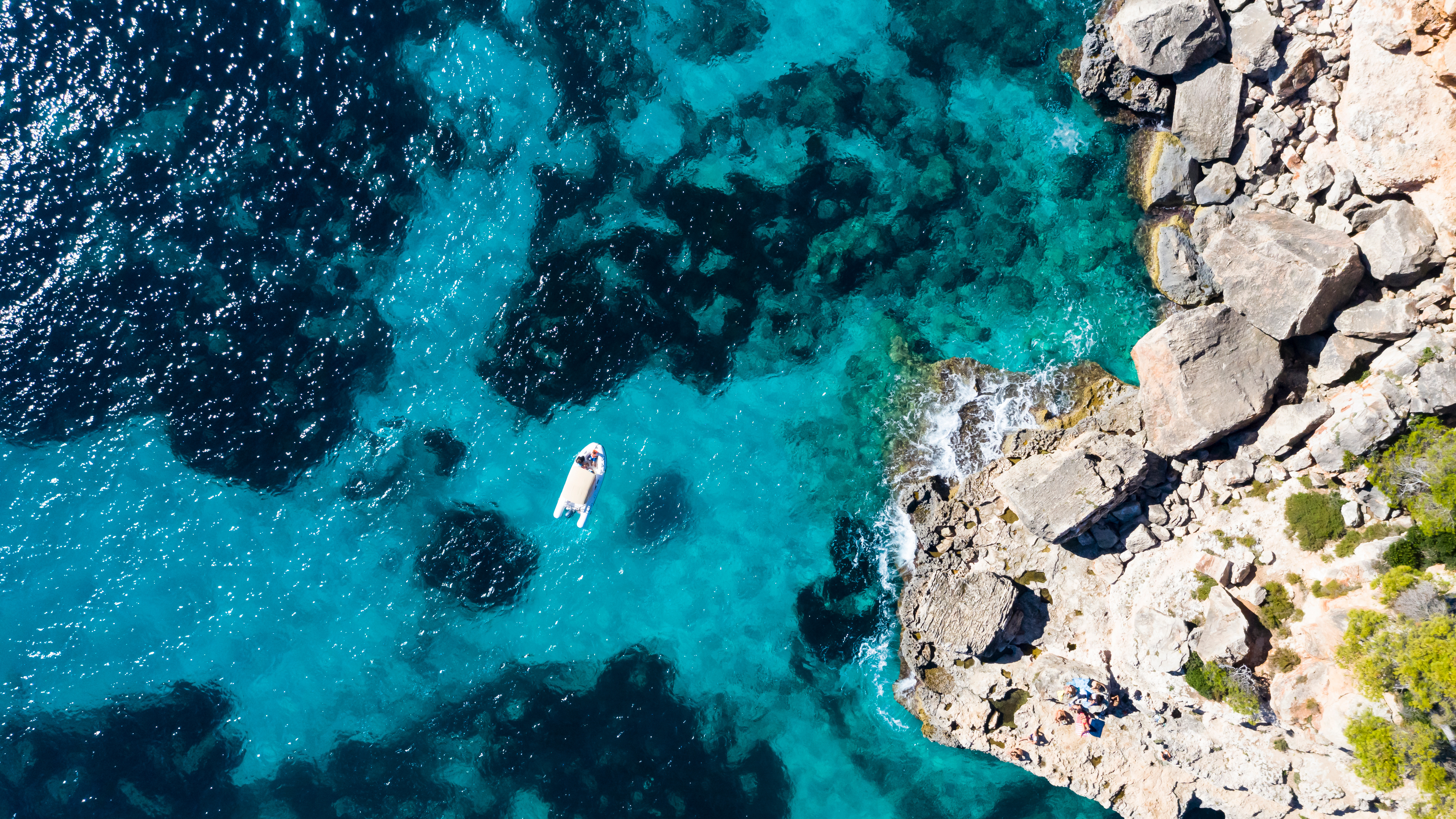 Luftaufnahme der Bucht von Cala Llombards. Türkisfarbenes Wasser im Wechsel mit tiefem blau.