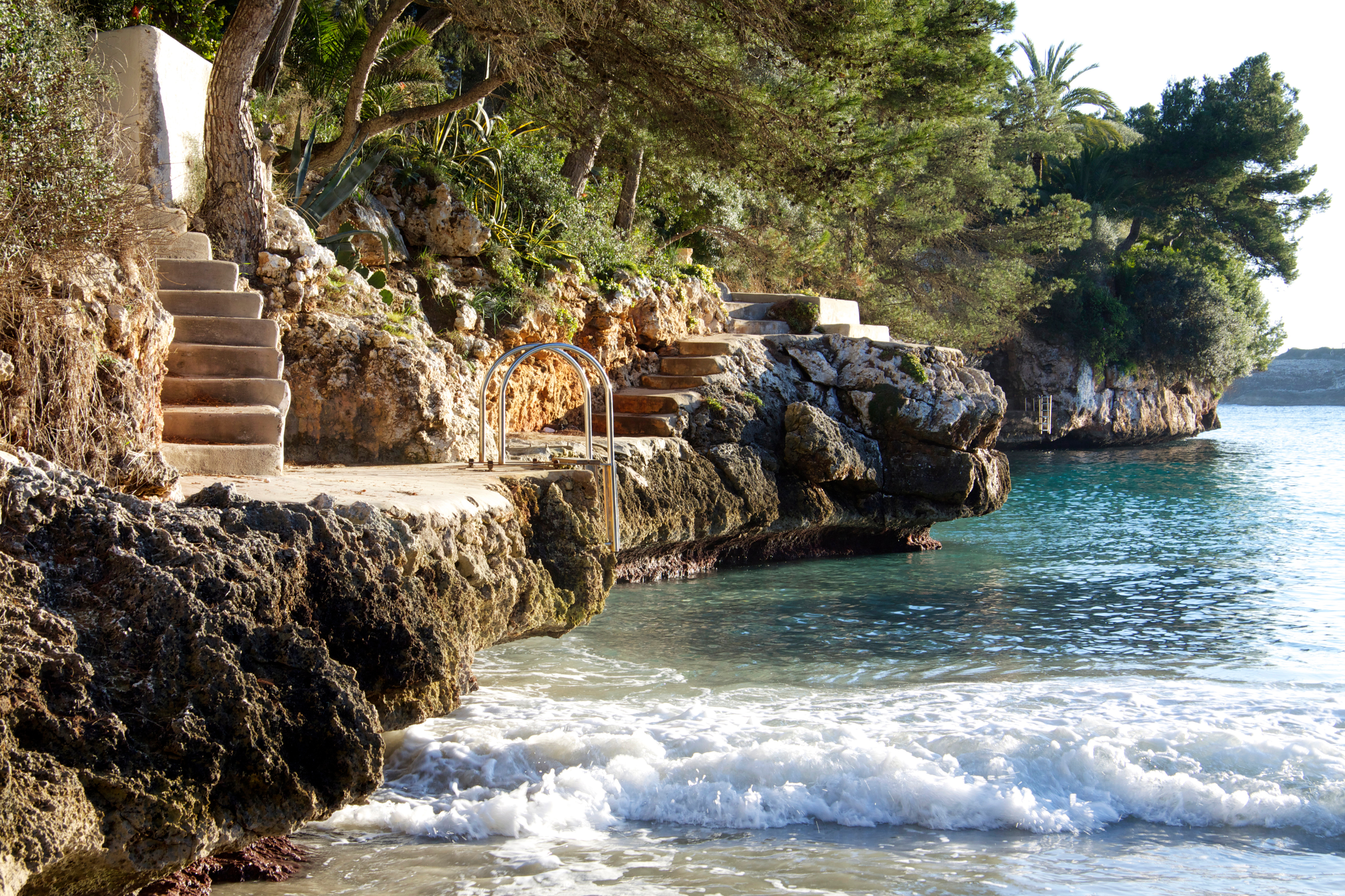 Stairs and bathing access on the rocky coast of Cala Serena