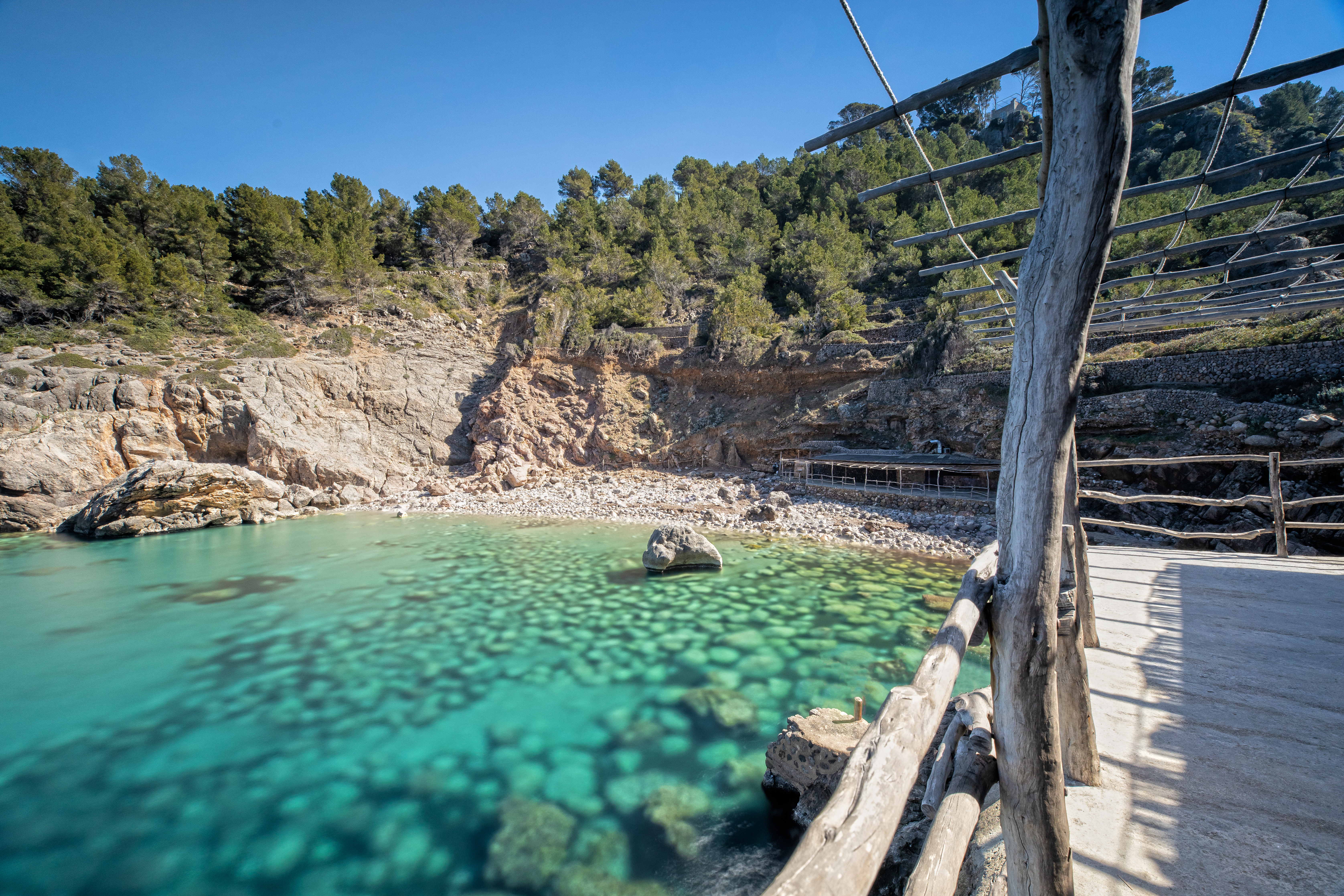 Small secluded bathing cove with wooden pier in Deia