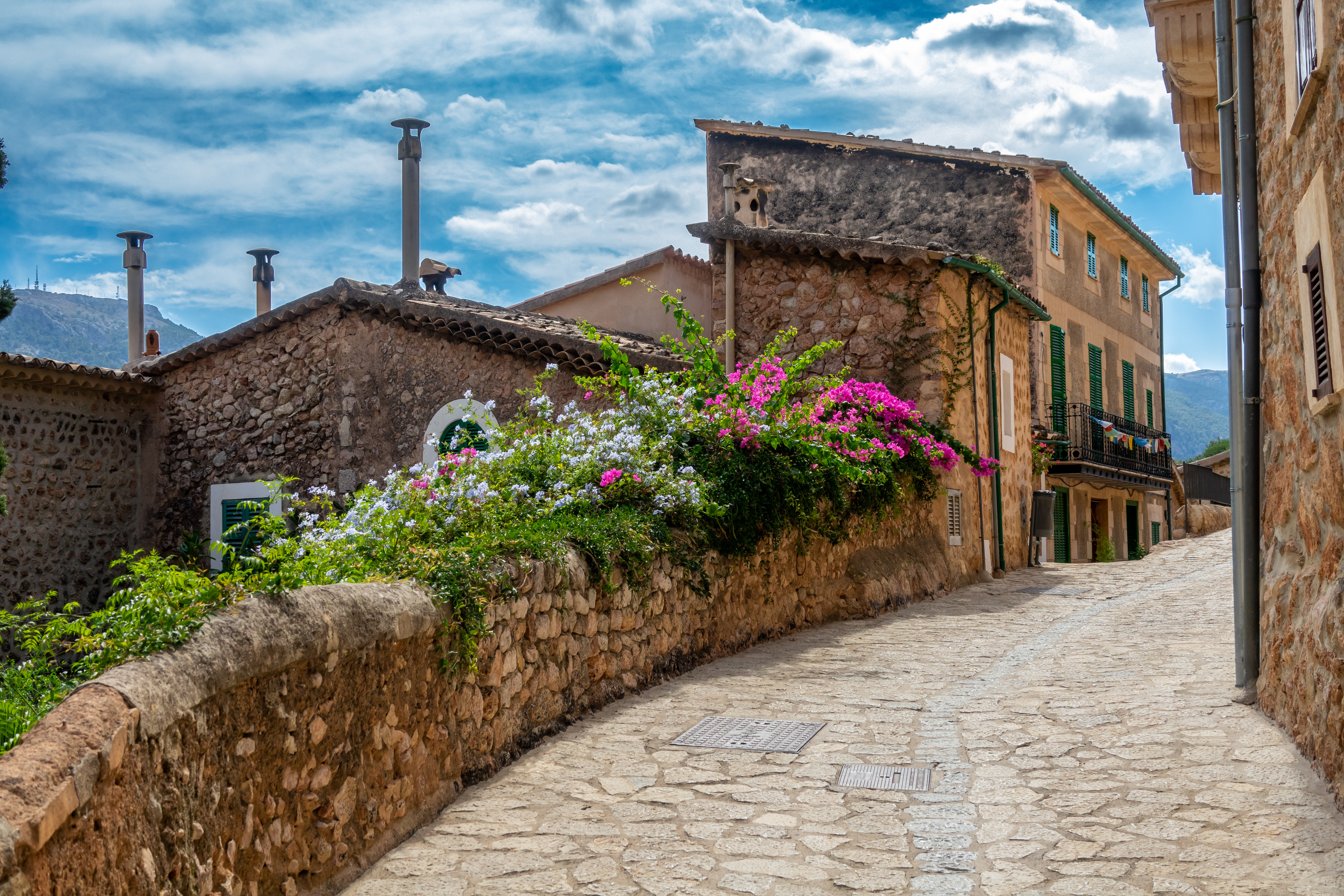 Cobblestone street with beautifully planted stone wall in Fornalutx