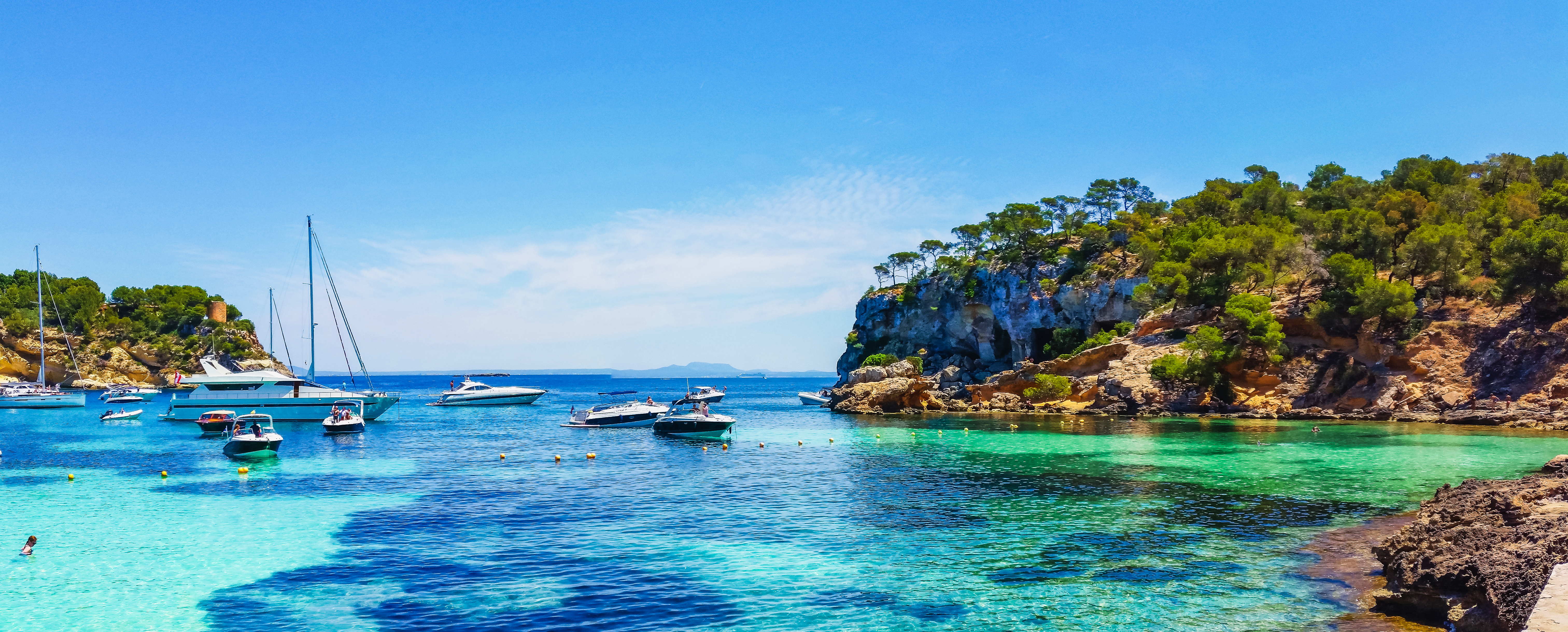 Small white sailboats in the turquoise bay of Portals Vells