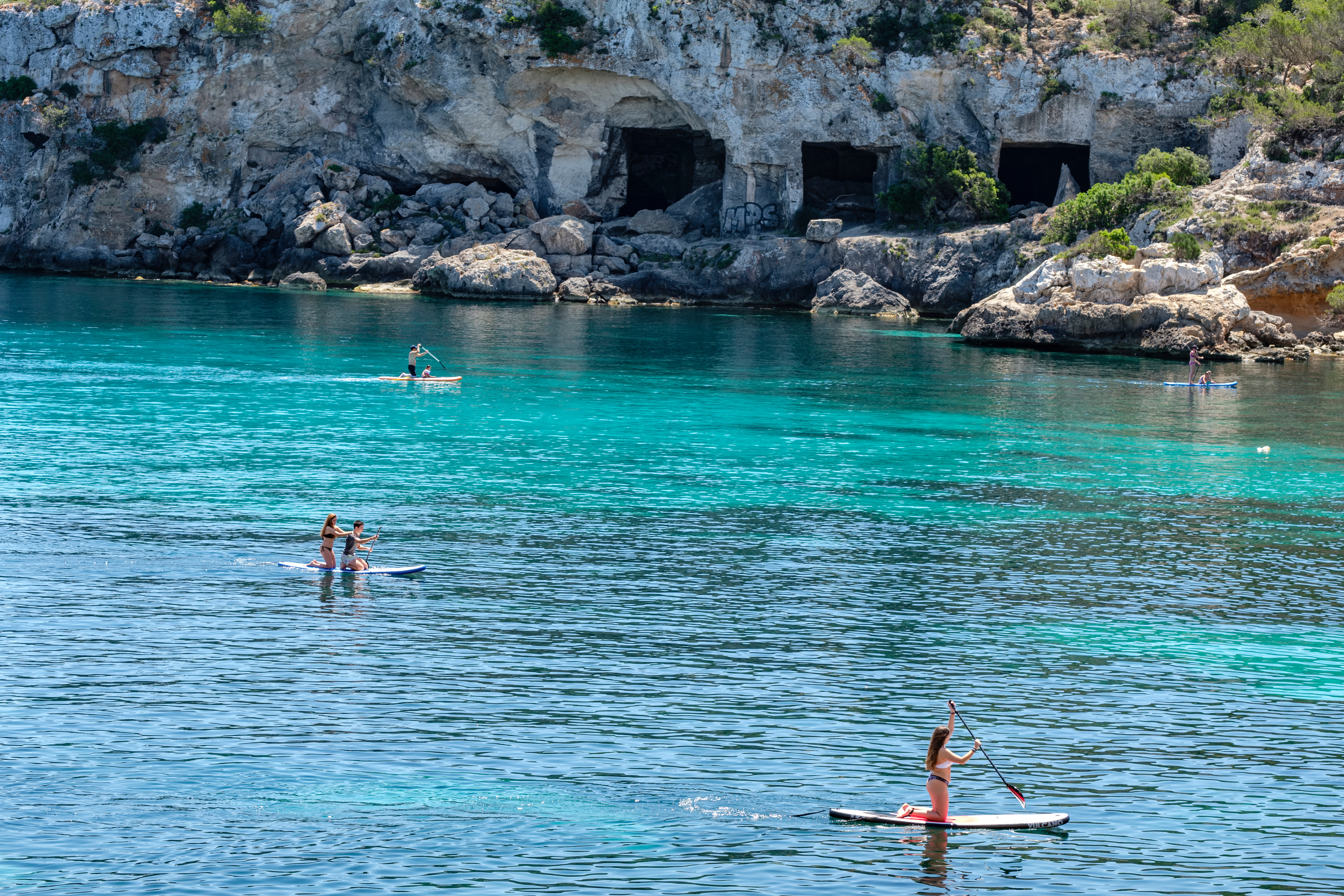 Kayaks frente a las entradas de las cuevas de Portals Vells