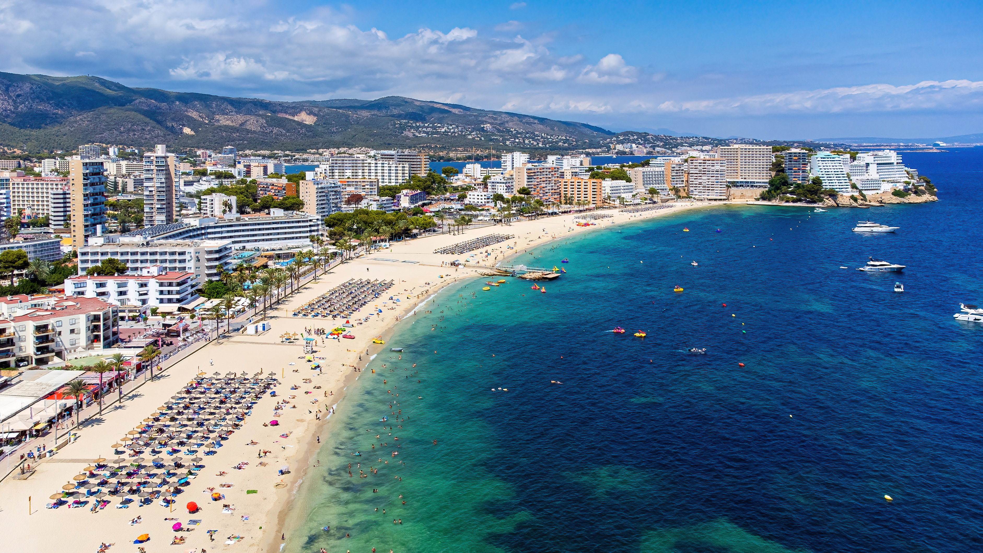 Rozległa plaża Torrenova z leżakami i parasolami